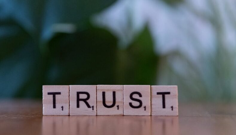 Wooden letter tiles spelling TRUST on a wooden surface, symbolizing integrity and values.